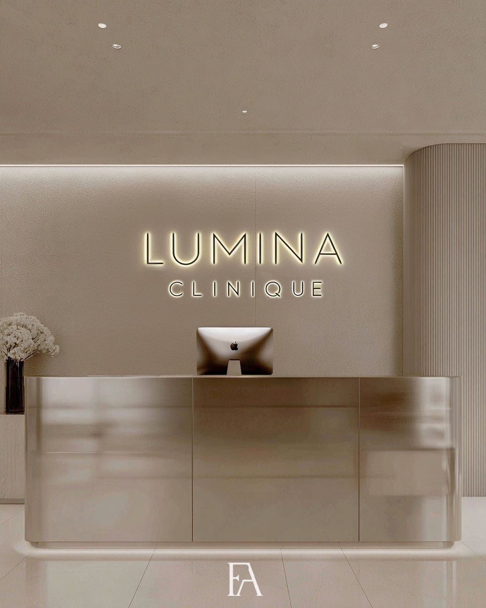 Comptoir de réception luxueux de Lumina Clinique avec logo rétroéclairé et habillage mural design.